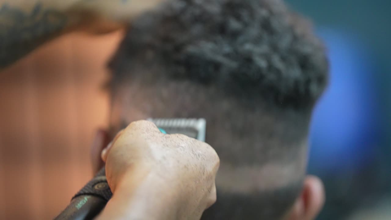 Barbeiro escovando o cabelo cacheado após o corte