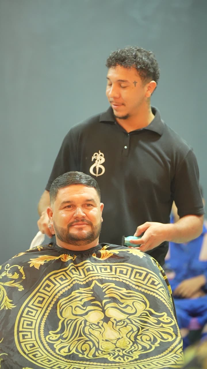 Cliente sentado diante do espelho enquanto o barbeiro trabalha atrás dele